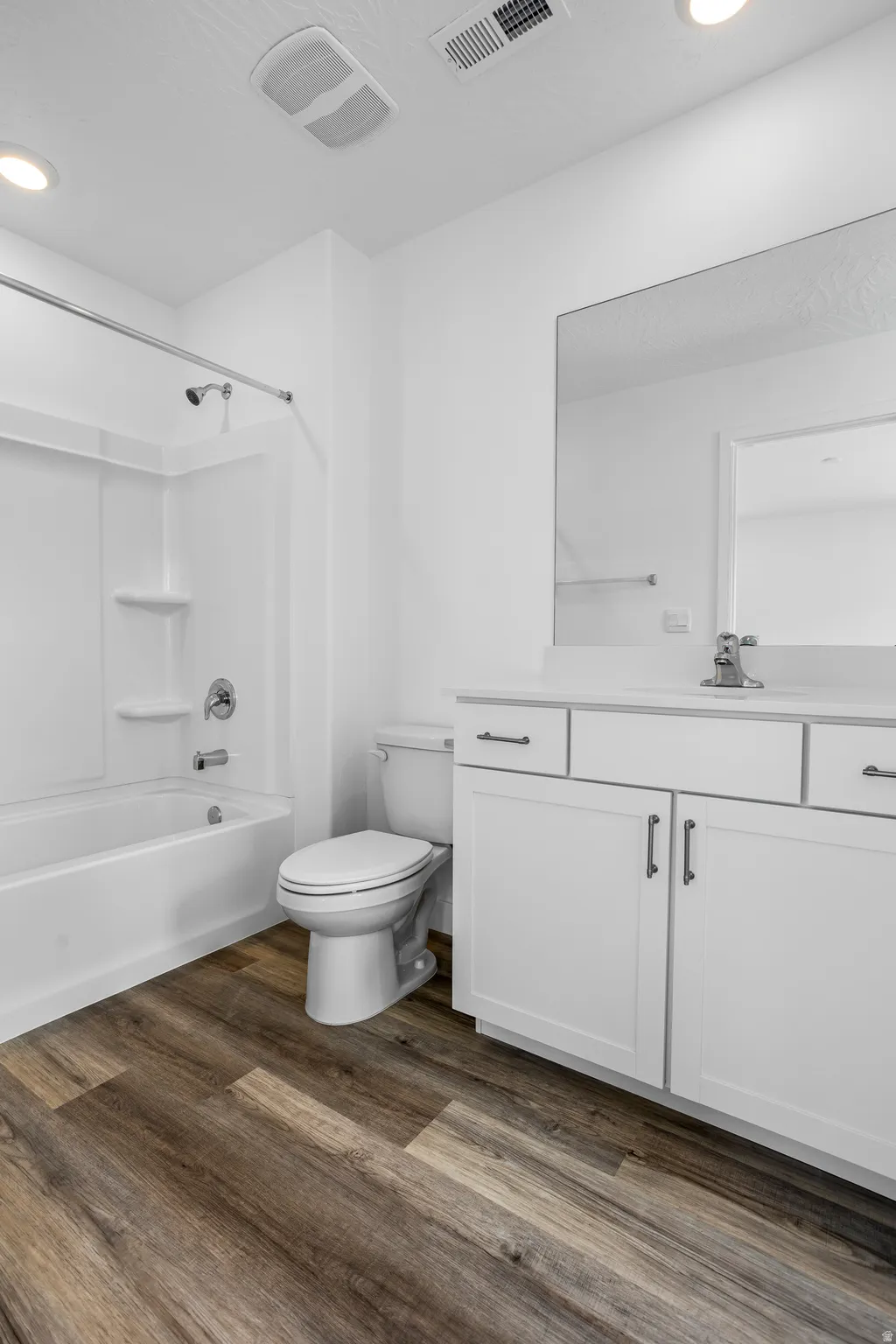 Bathroom with vanity, dark wood-type flooring,  shower combination, and recessed lighting