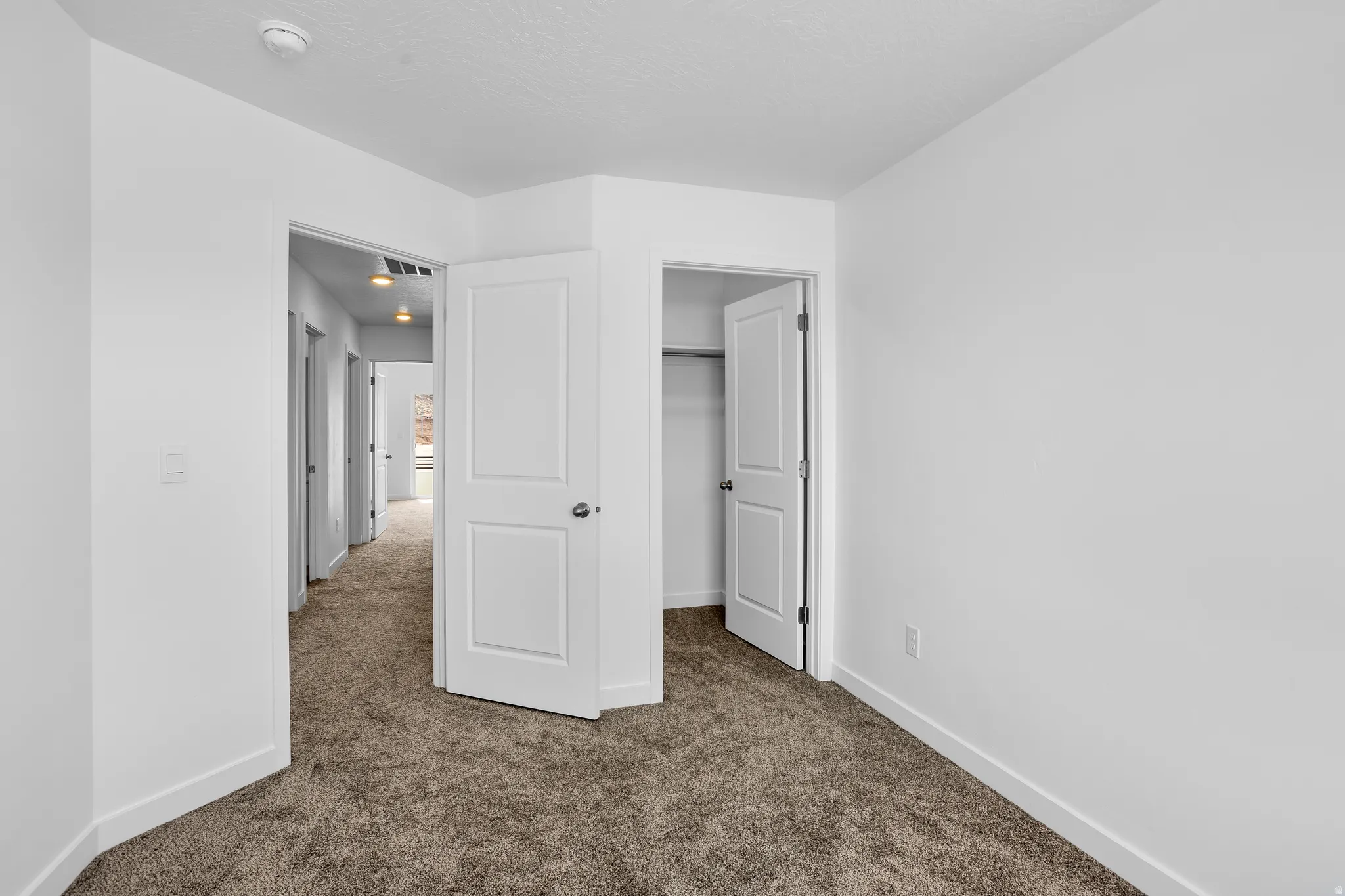 Unfurnished bedroom featuring dark colored carpet and a walk in closet