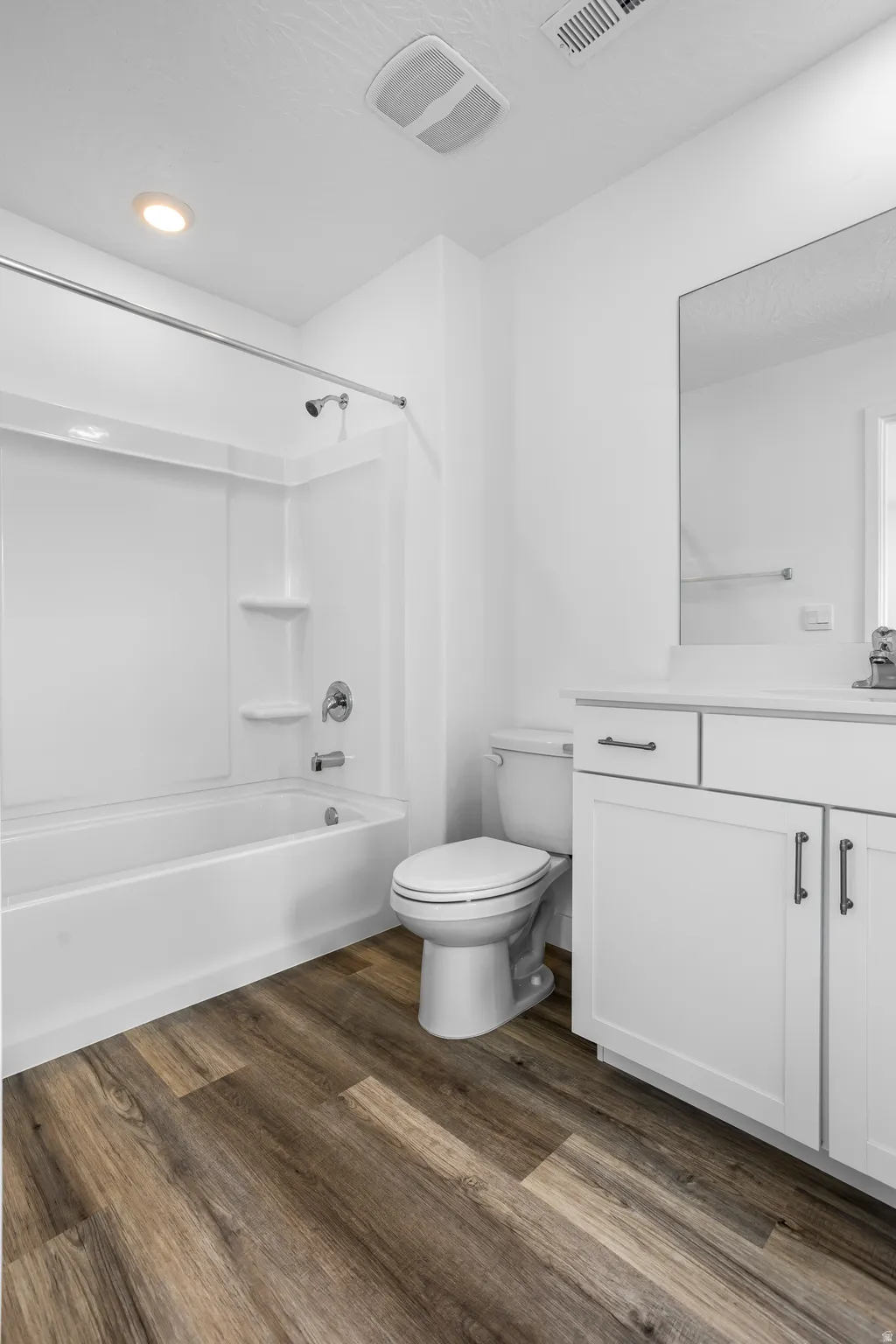Full bath featuring tub / shower combination, vanity, and dark wood-type flooring