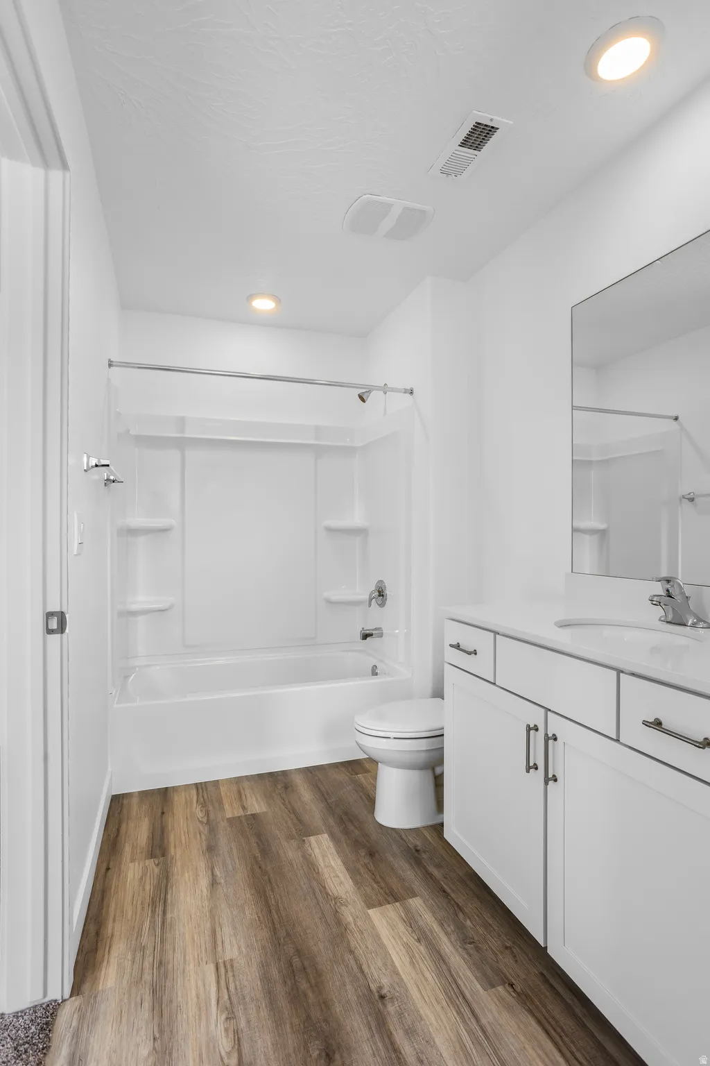 Bathroom with dark wood-style flooring, vanity, bathtub / shower combination, and recessed lighting