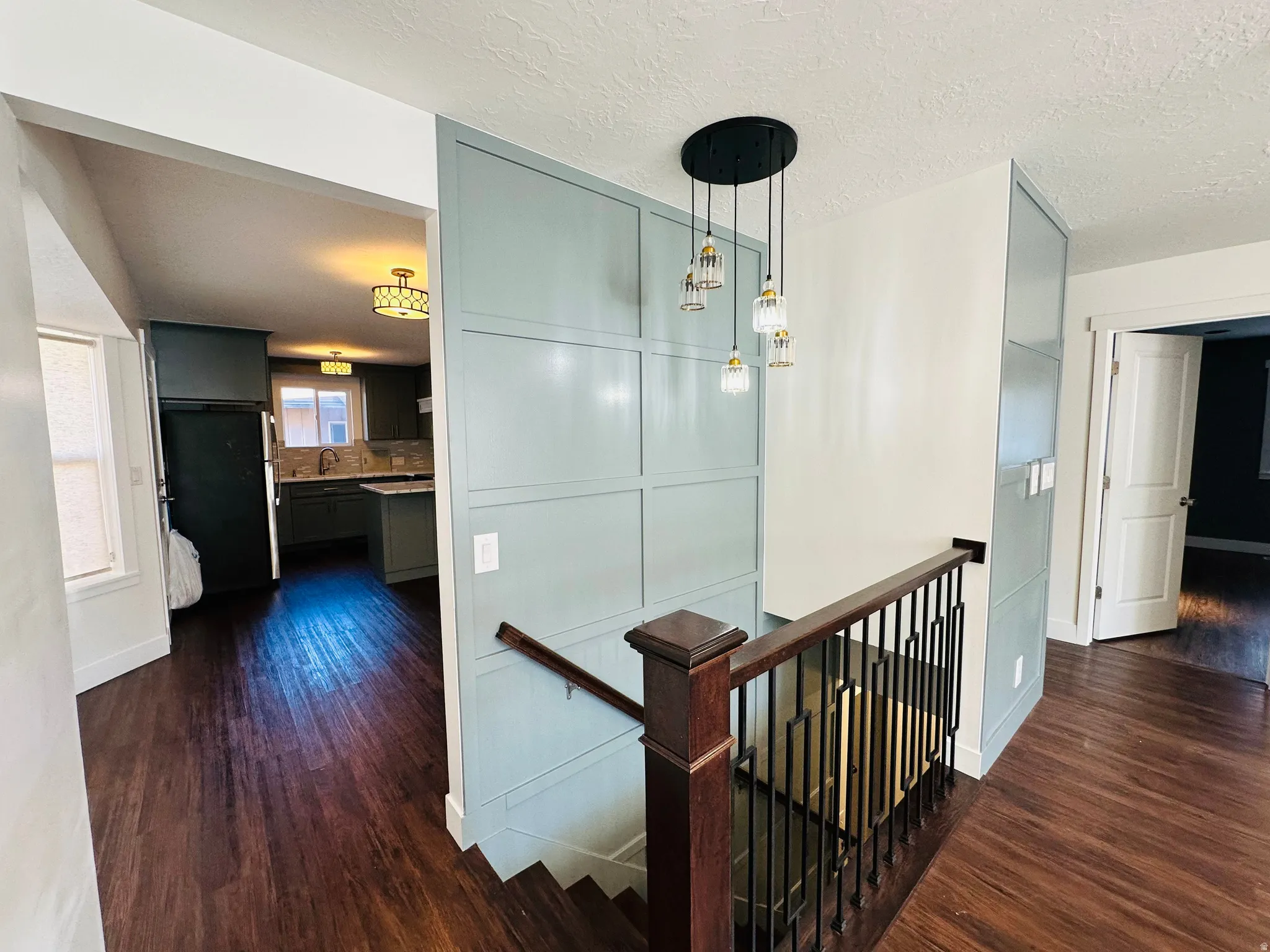 Hallway featuring an upstairs landing, dark wood-style flooring, and a textured ceiling