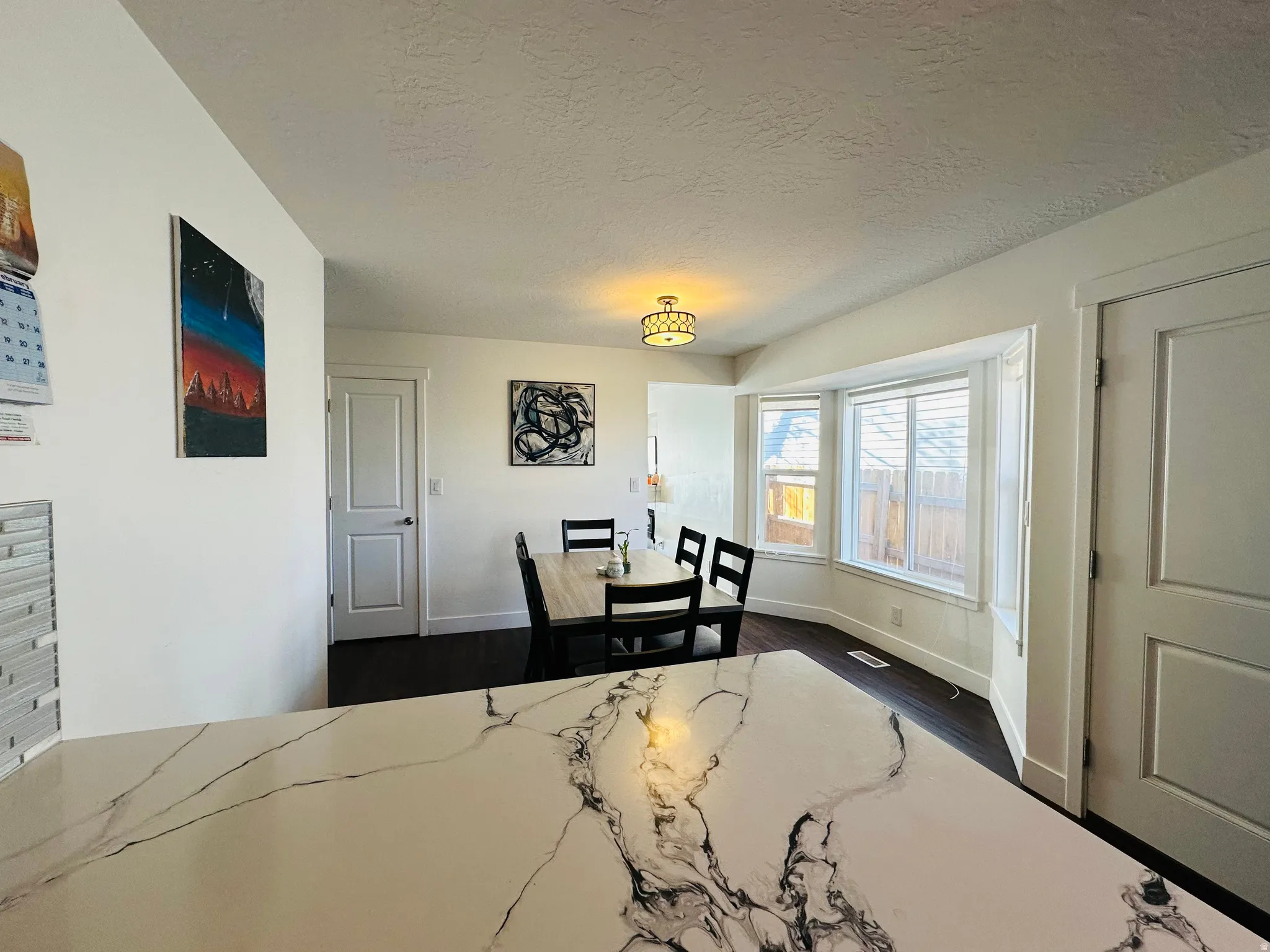 Dining room featuring a textured ceiling and dark wood-style flooring