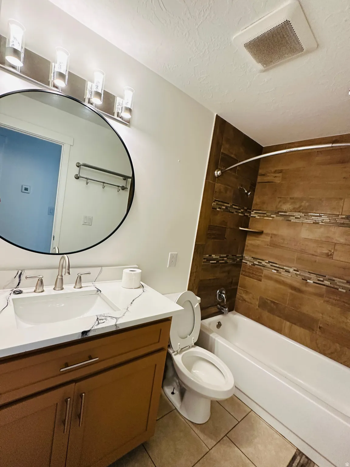 Full bathroom with vanity, shower / bathtub combination, light tile patterned floors, and a textured ceiling