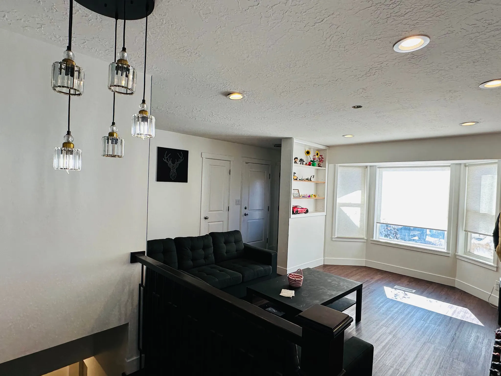 Living area featuring a textured ceiling, wood finished floors, built in shelves, and recessed lighting