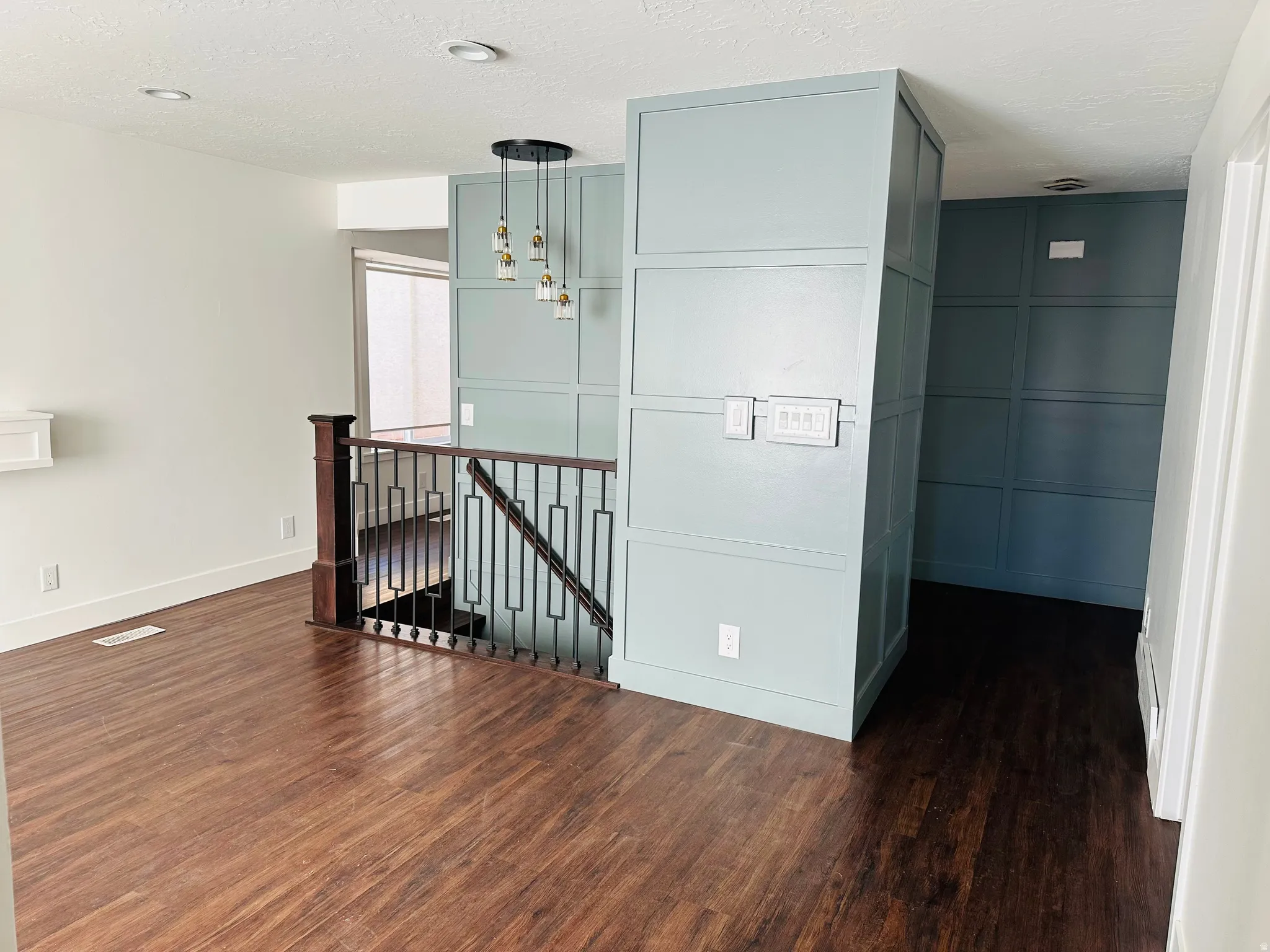 Hall featuring an upstairs landing, dark wood-style flooring, and a textured ceiling