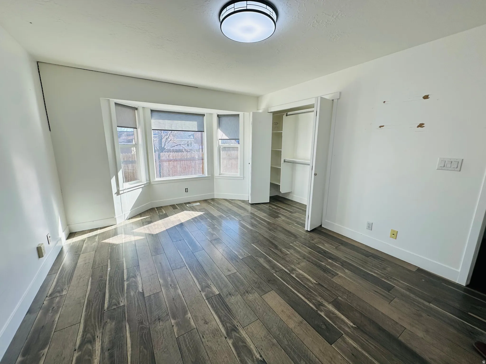 Unfurnished bedroom featuring a closet and dark wood-type flooring