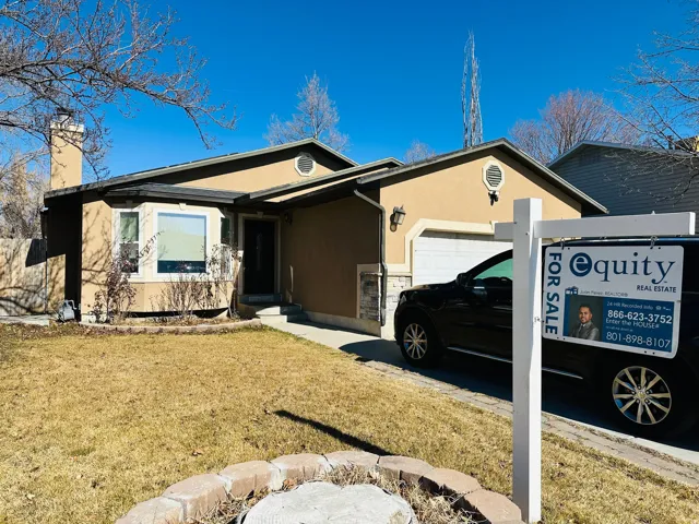Single story home featuring an attached garage, stucco siding, a chimney, and a front yard
