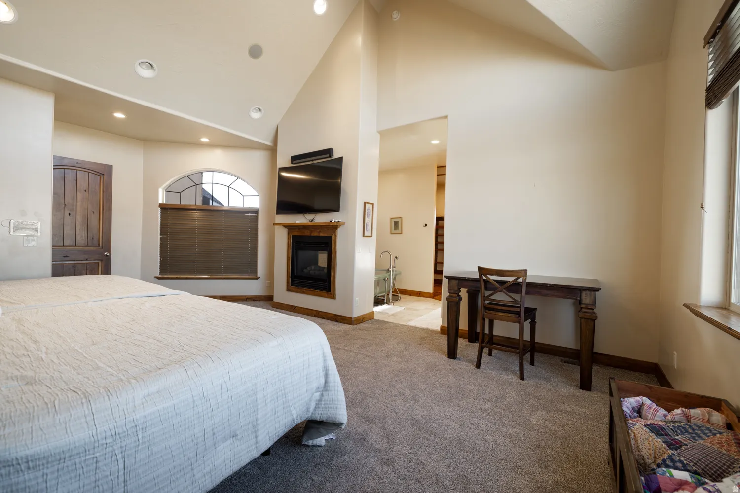 Bedroom with lofted ceiling, carpet, a multi sided fireplace, recessed lighting, and ensuite bath