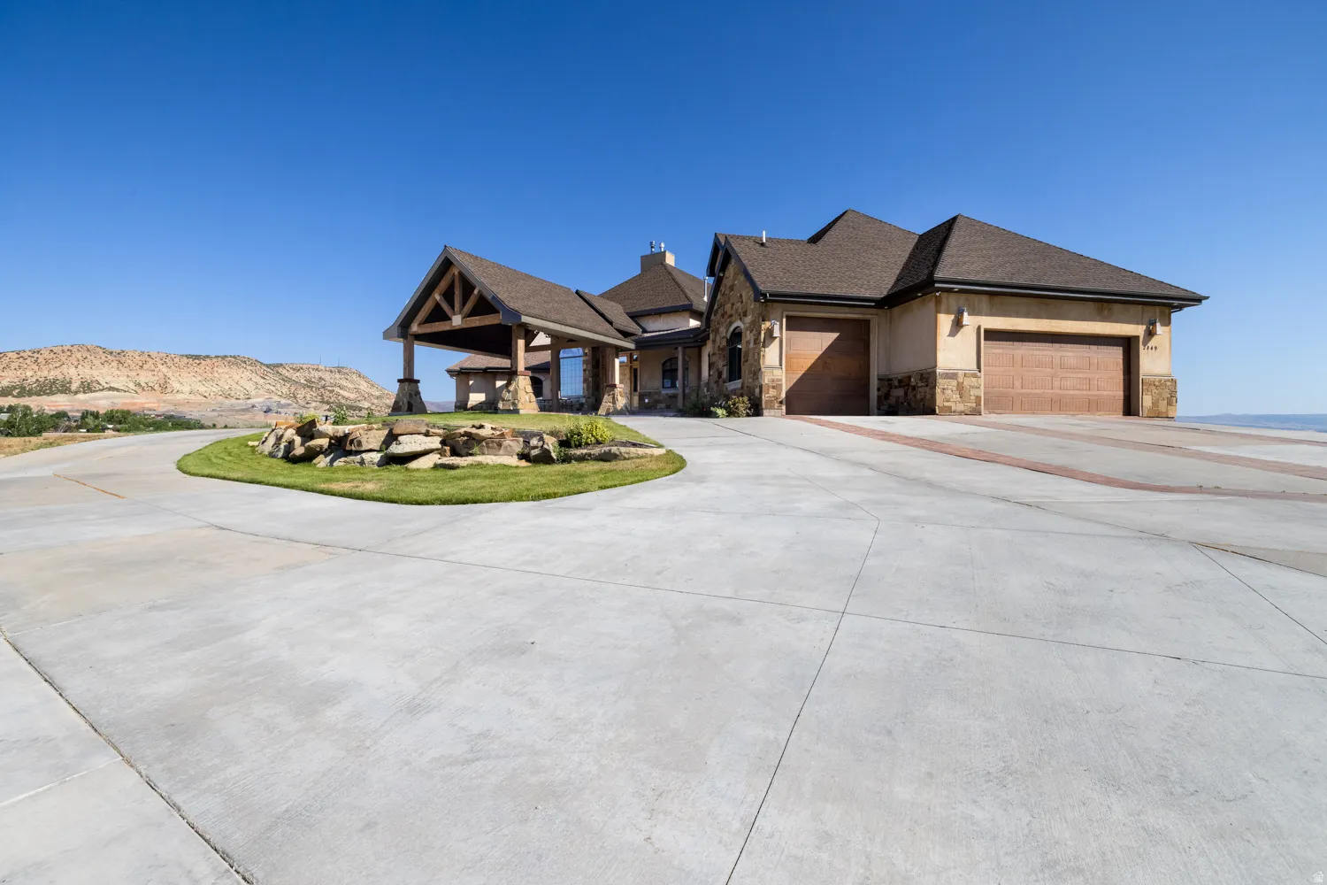 View of front of house featuring stone siding, concrete driveway, an attached garage, a mountain view, and stucco siding