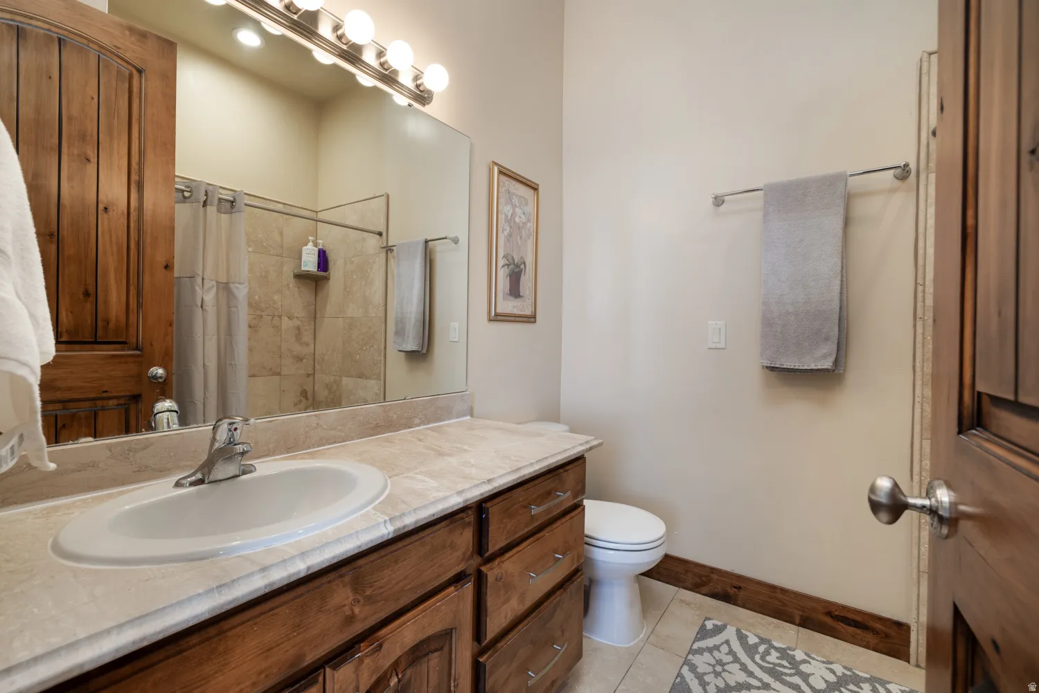 Full bath with vanity, a shower with shower curtain, and light tile patterned flooring
