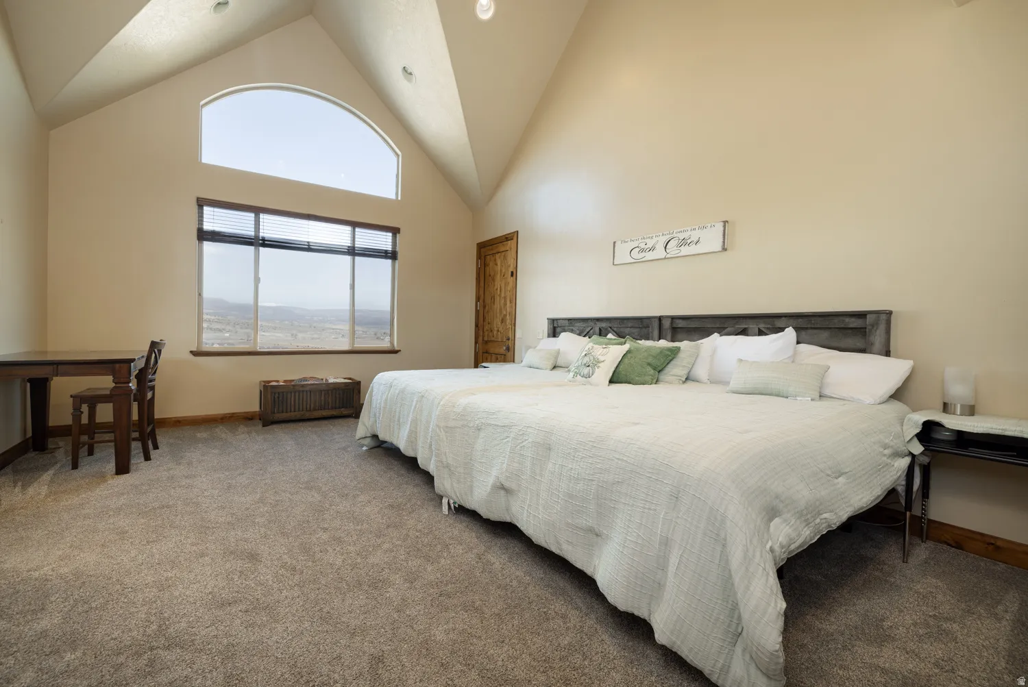 Carpeted bedroom featuring a high ceiling and baseboards
