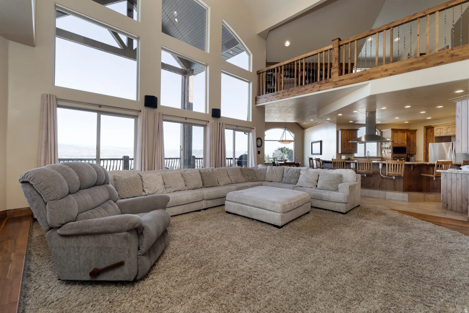 Living room with wood finished floors, recessed lighting, and a high ceiling