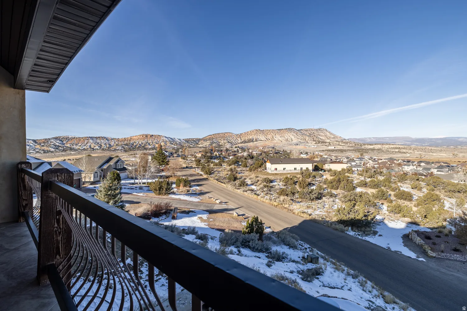 Snow covered back of property featuring a mountain view and a residential view