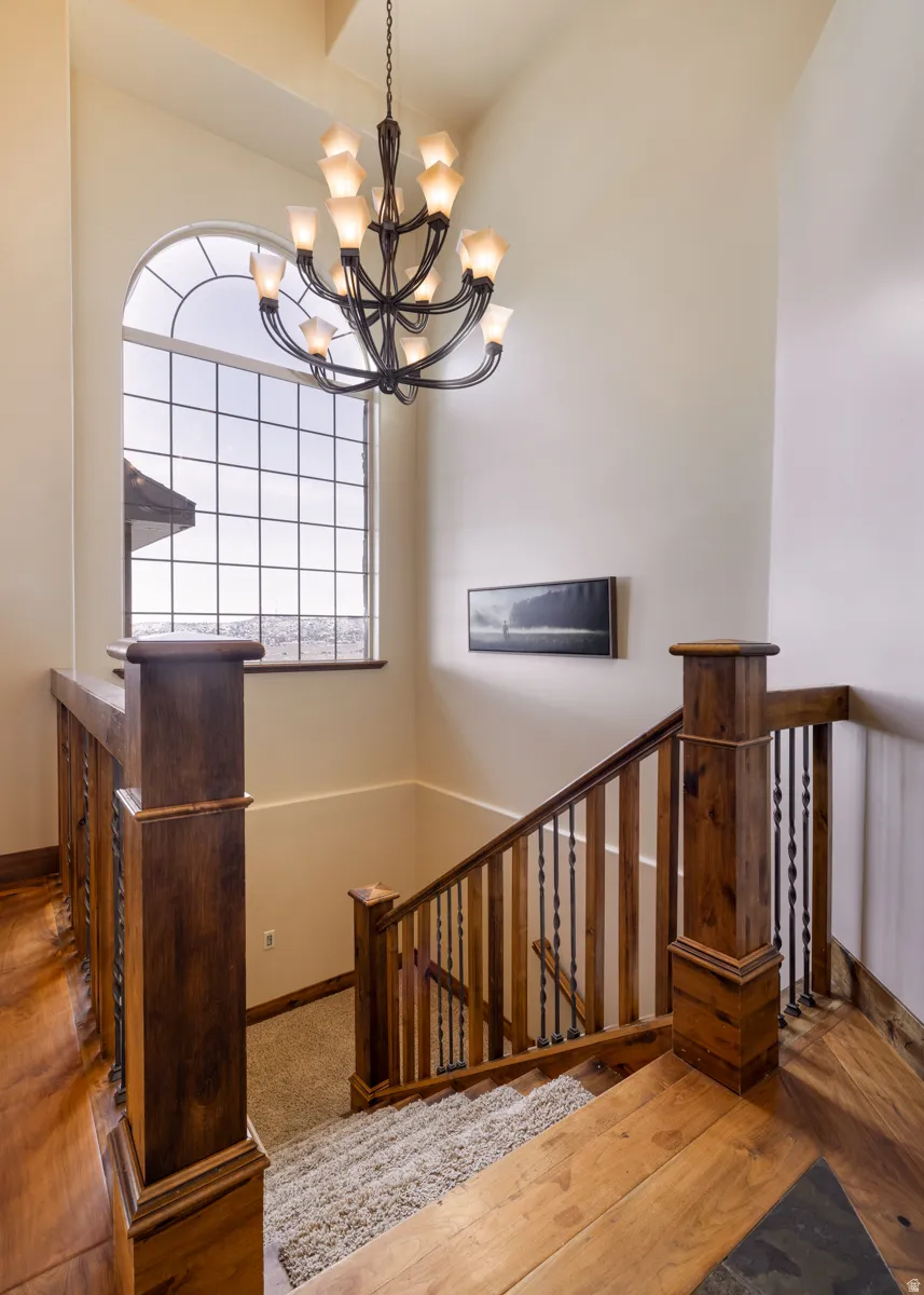 Stairway with hardwood / wood-style flooring and suspended lighting