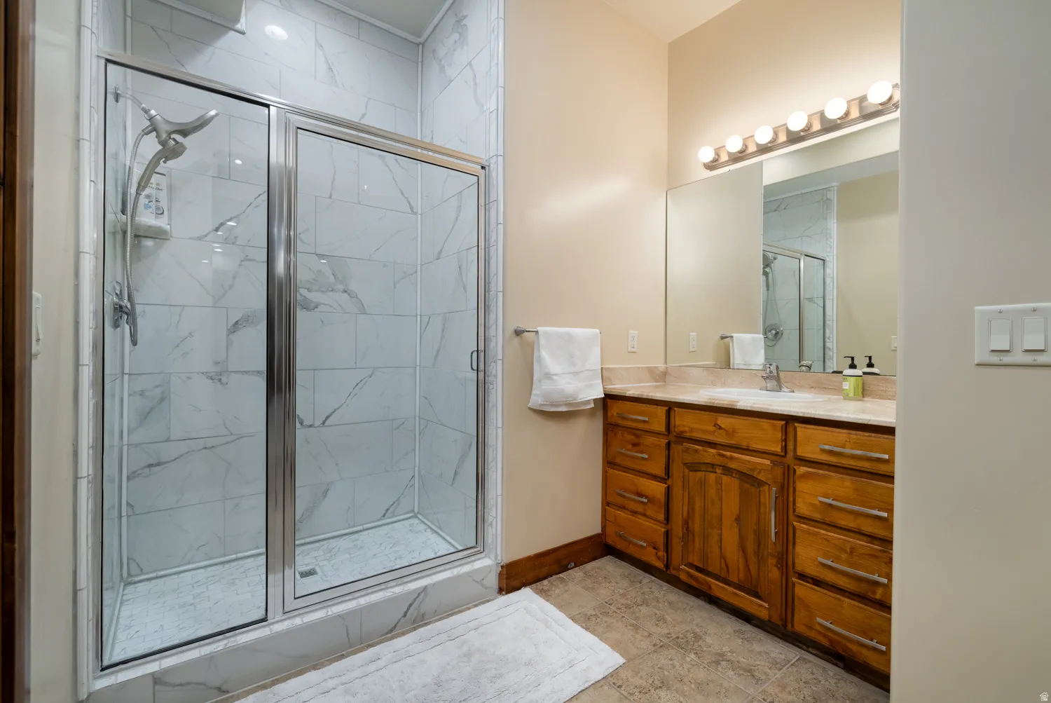Full bathroom featuring vanity and a marble finish shower