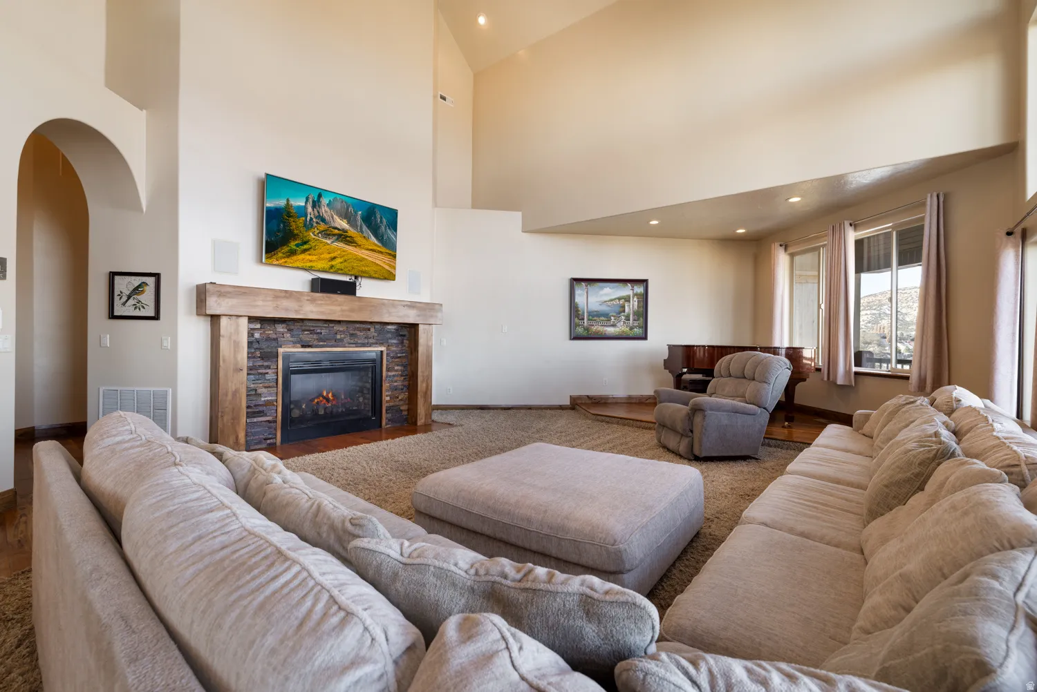 Carpeted living area featuring arched walkways, a fireplace, a high ceiling, and recessed lighting