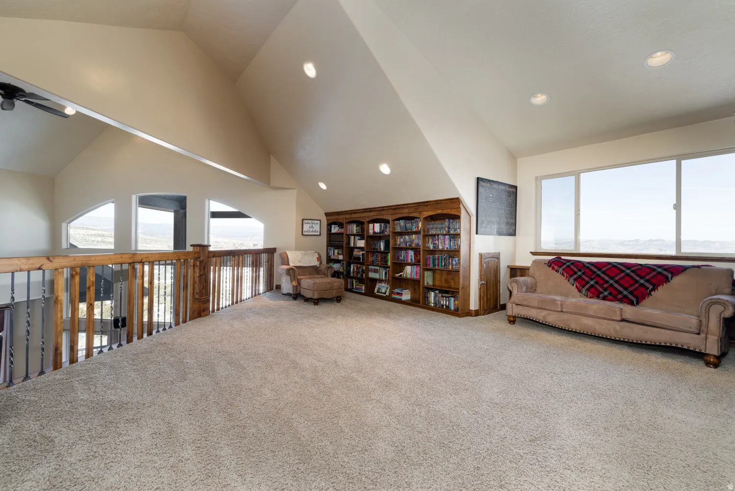 Sitting room with carpet floors, vaulted ceiling, ceiling fan, built in shelves, and recessed lighting