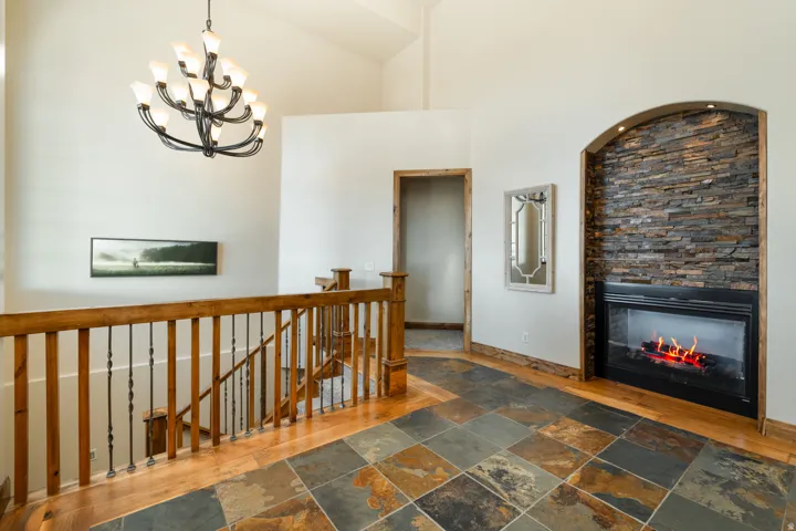 Corridor featuring an upstairs landing, stone tile flooring, a high ceiling, and hanging lights