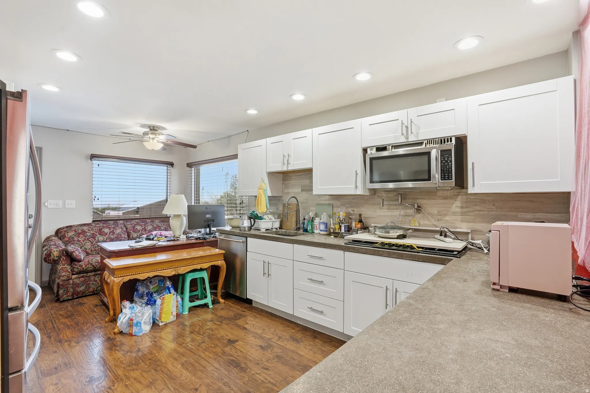 Kitchen with white cabinets, stainless steel appliances, recessed lighting, dark wood-style floors, and tasteful backsplash
