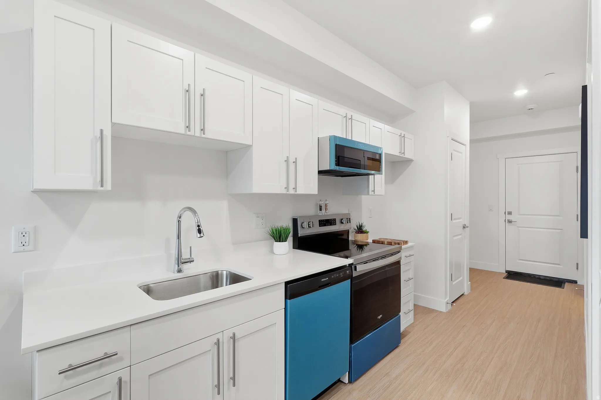 Kitchen with white cabinets, electric range, dishwashing machine, light wood finished floors, and recessed lighting