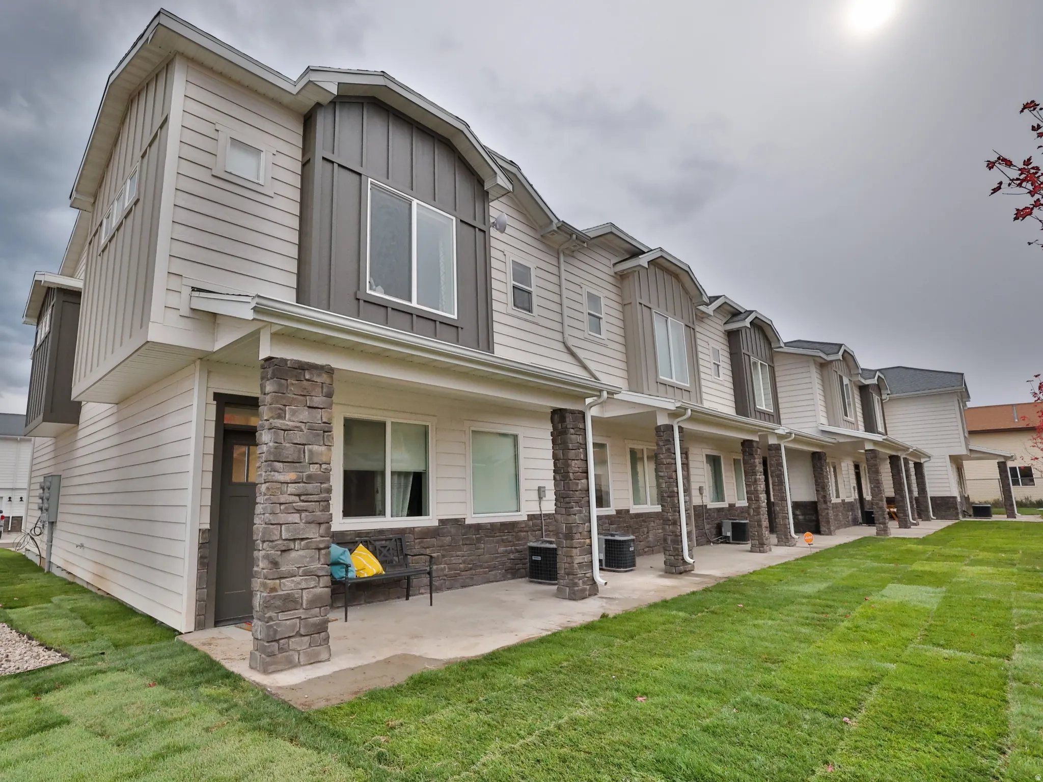 Rear view of property featuring stone siding, a yard, board and batten siding, and a residential view