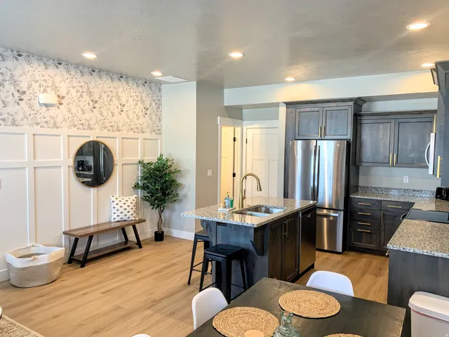 Kitchen featuring a decorative wall, light stone countertops, light wood-style floors, stainless steel appliances, and a breakfast bar area