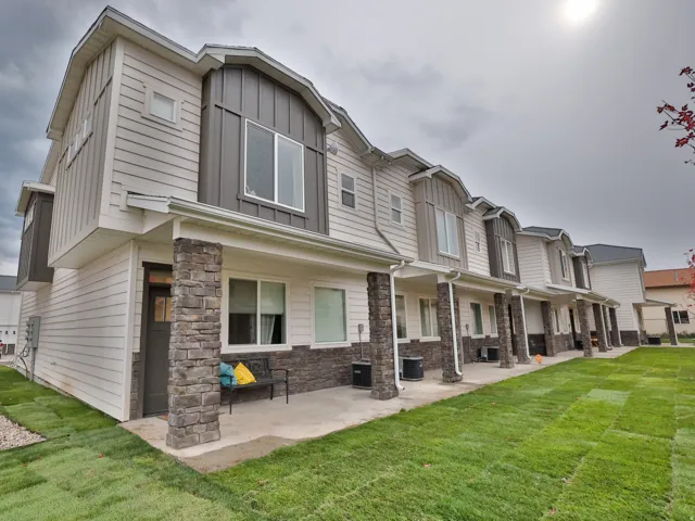 Rear view of property featuring stone siding, a yard, board and batten siding, and a residential view
