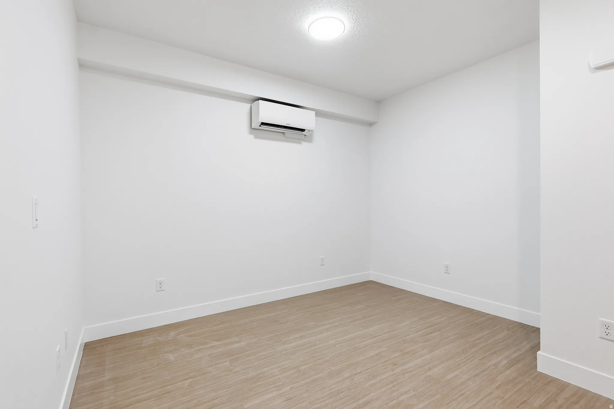 Living room with light wood-style flooring and a wall mounted mini split
