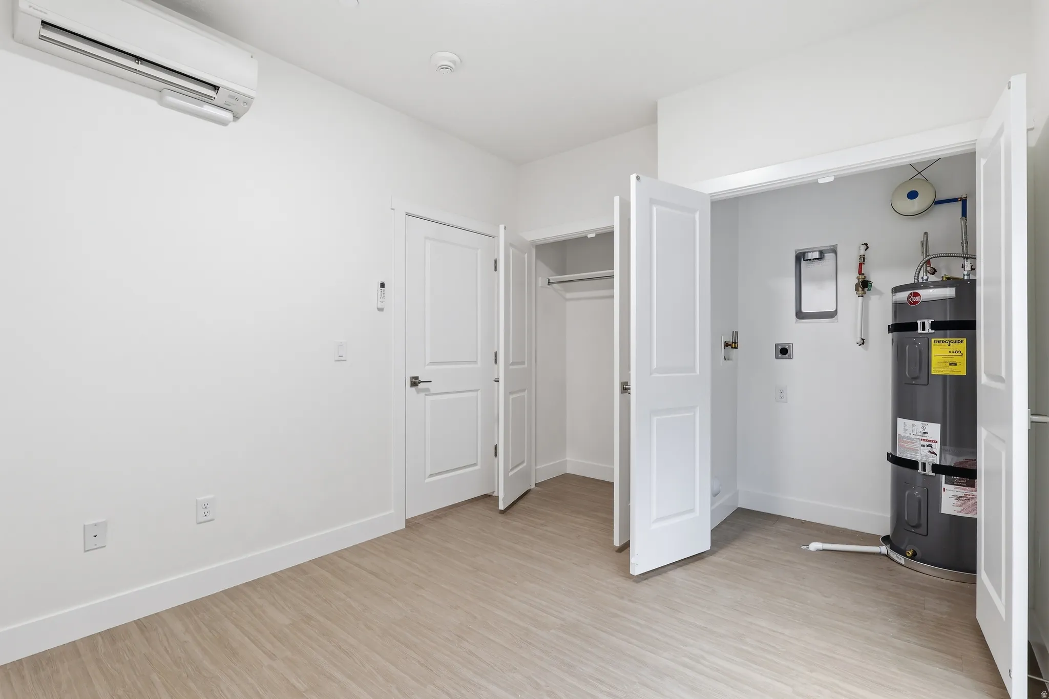 Bedroom with secured water heater, light wood-style flooring, and a closet
