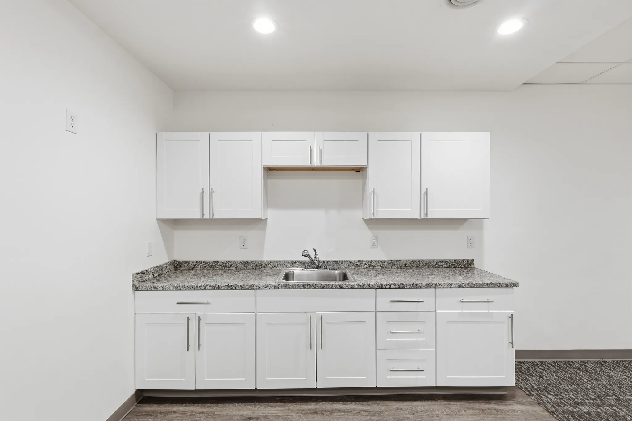 Club kitchen with white cabinets and dark wood finished floors