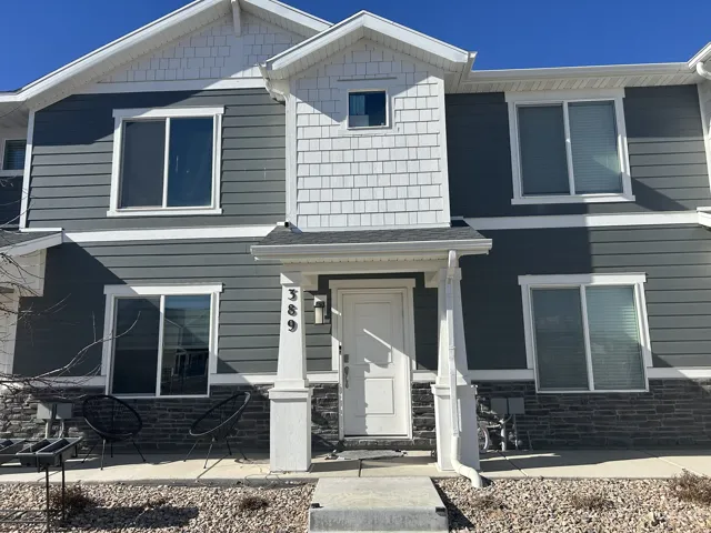 View of front of house featuring stone siding and roof with shingles