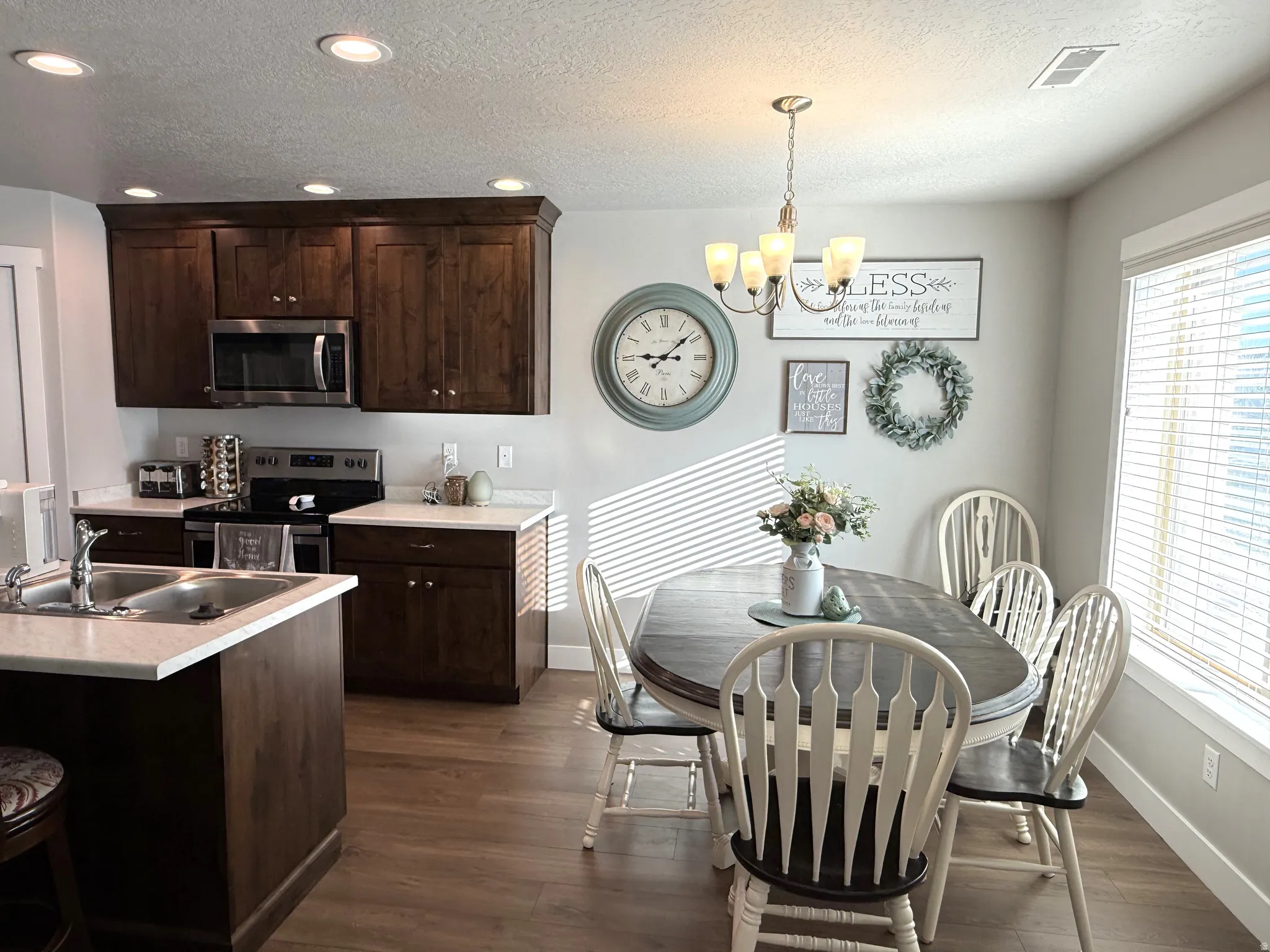 Kitchen featuring dark wood finish cabinets, light countertops, stainless steel appliances, dark wood finished floors, and a textured ceiling