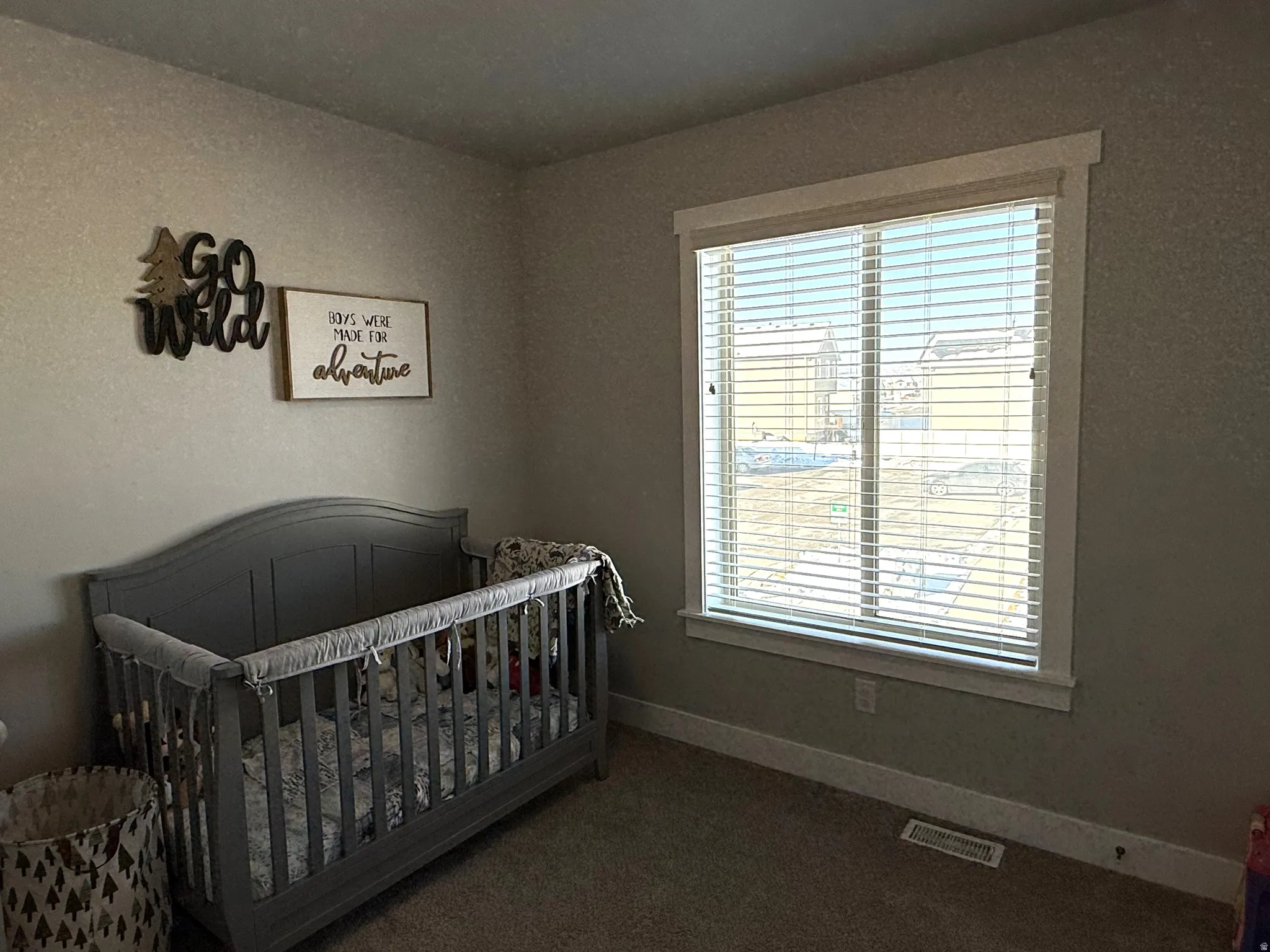 Bedroom featuring a crib and dark colored carpet