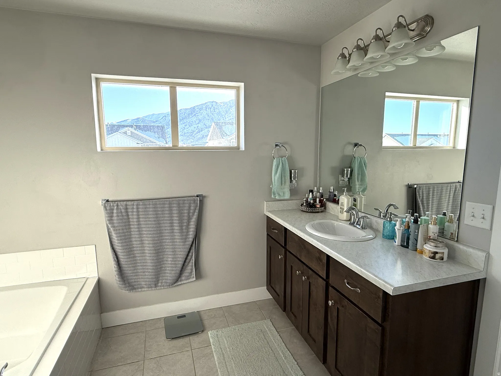 Bathroom featuring vanity, light tile patterned flooring, healthy amount of natural light, and a garden tub