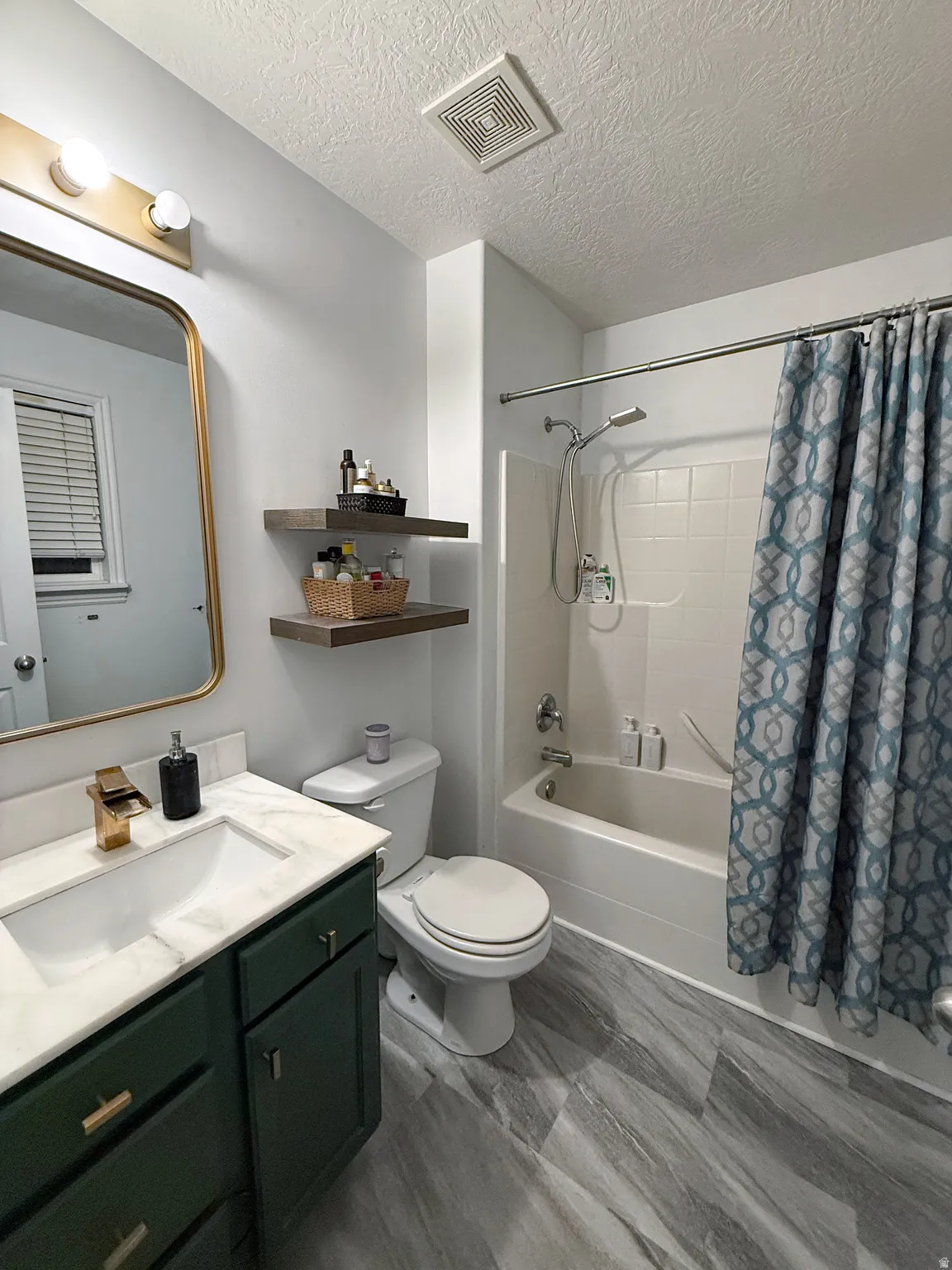 Full bathroom with vanity, shower / tub combo, and a textured ceiling