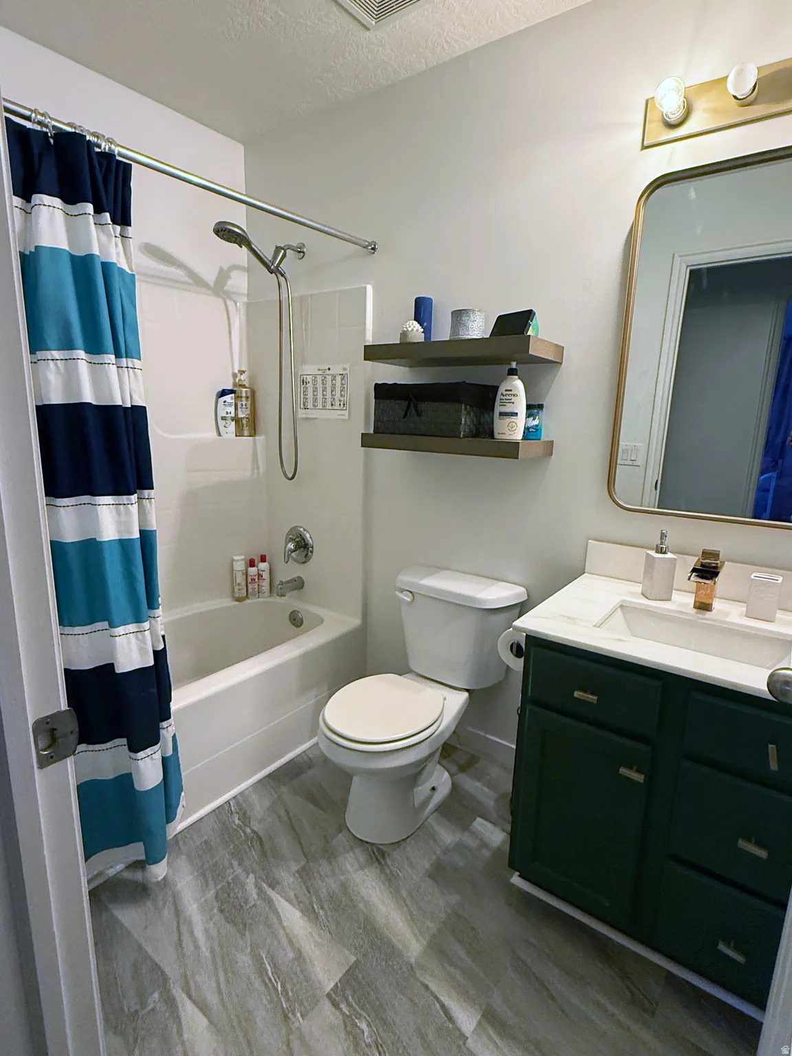 Full bath with vanity, a textured ceiling, and shower / bathtub combination with curtain