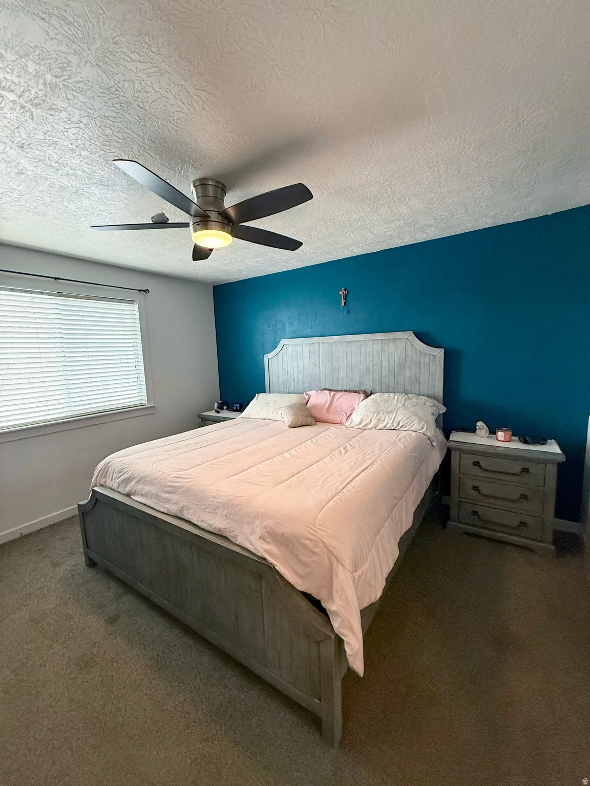 Bedroom with carpet floors, a textured ceiling, and ceiling fan
