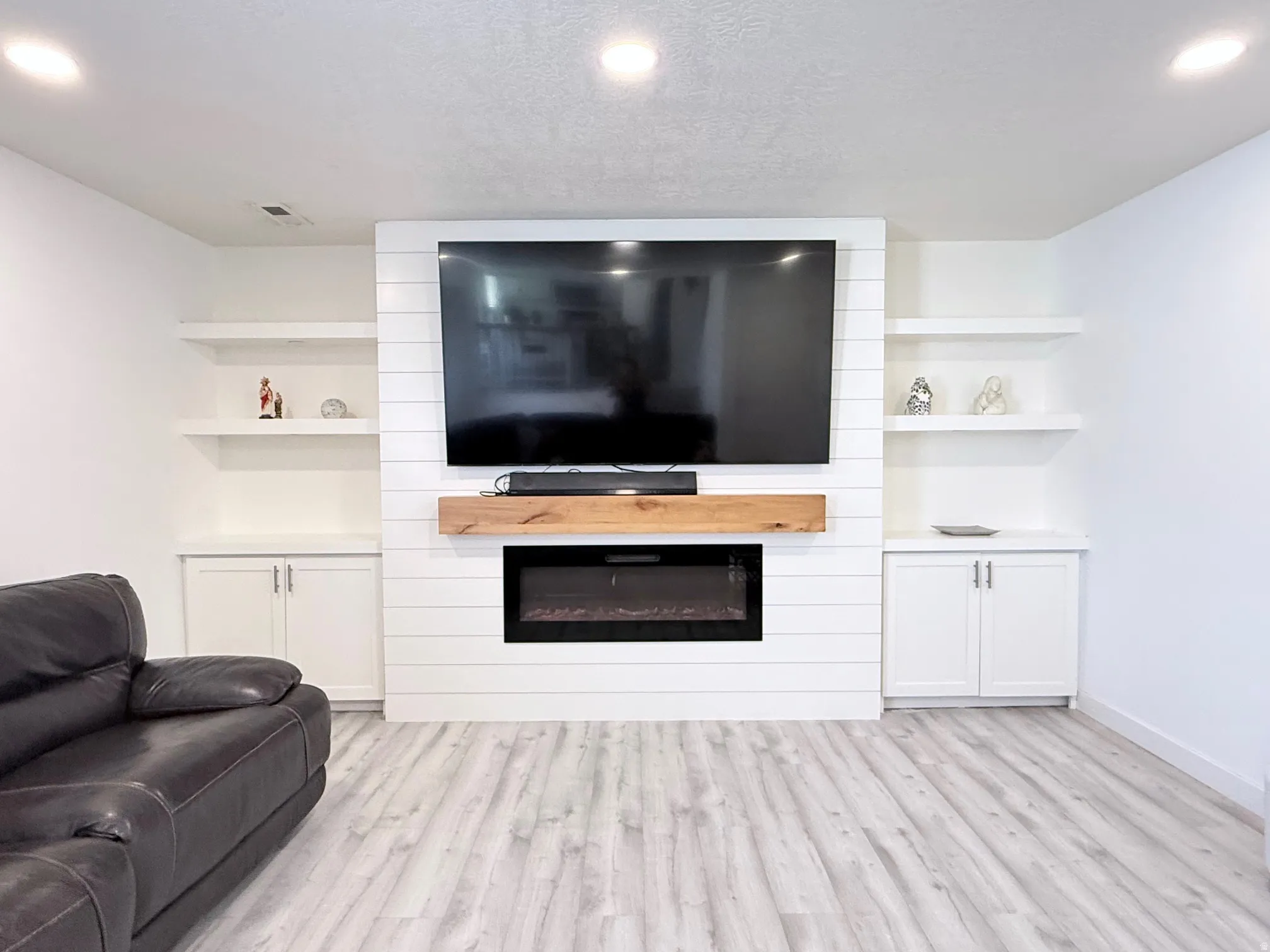 Living room with light wood-type flooring, a fireplace, and built in shelves