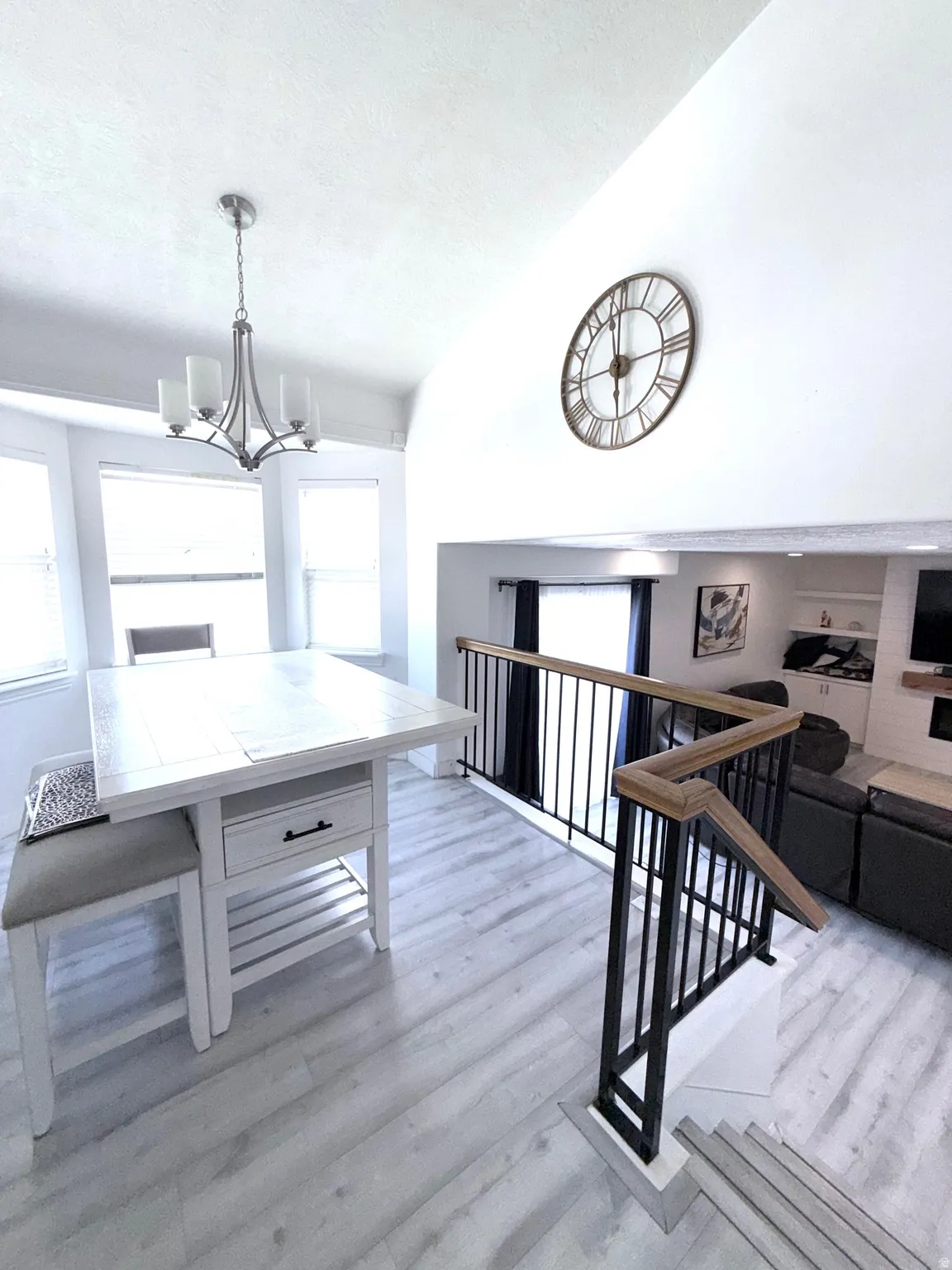 Dining room featuring lofted ceiling, light wood finished floors, and suspended lighting