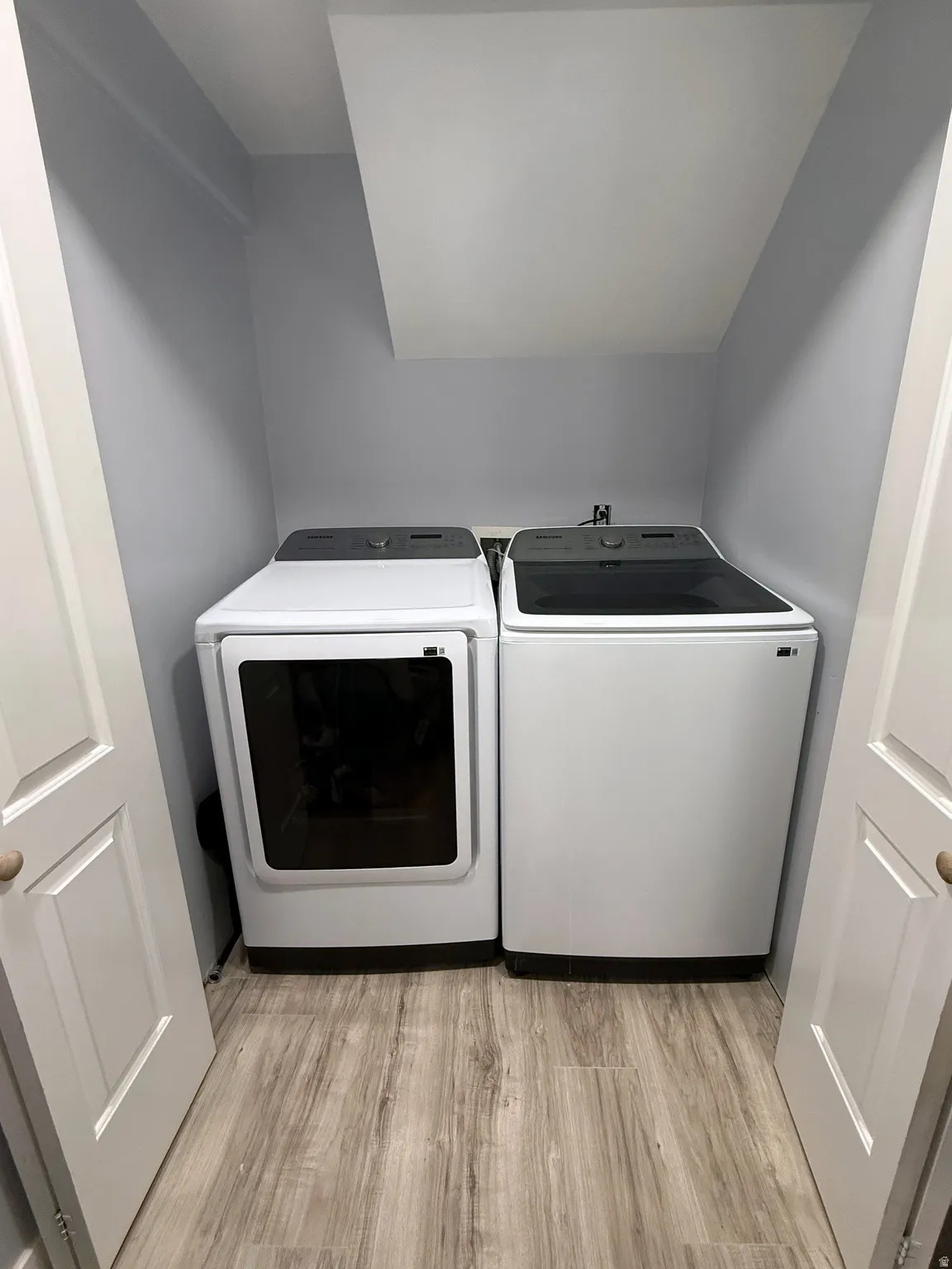 Laundry area with light wood-style flooring and washer and dryer