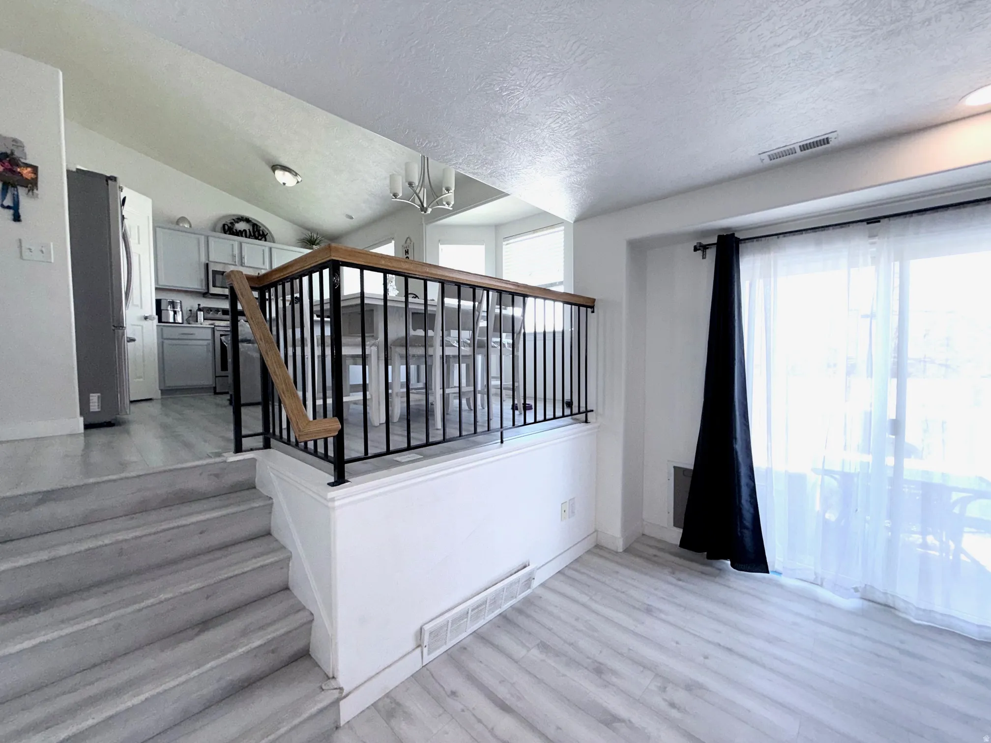 Stairway featuring wood finished floors, suspended lighting, plenty of natural light, and a textured ceiling