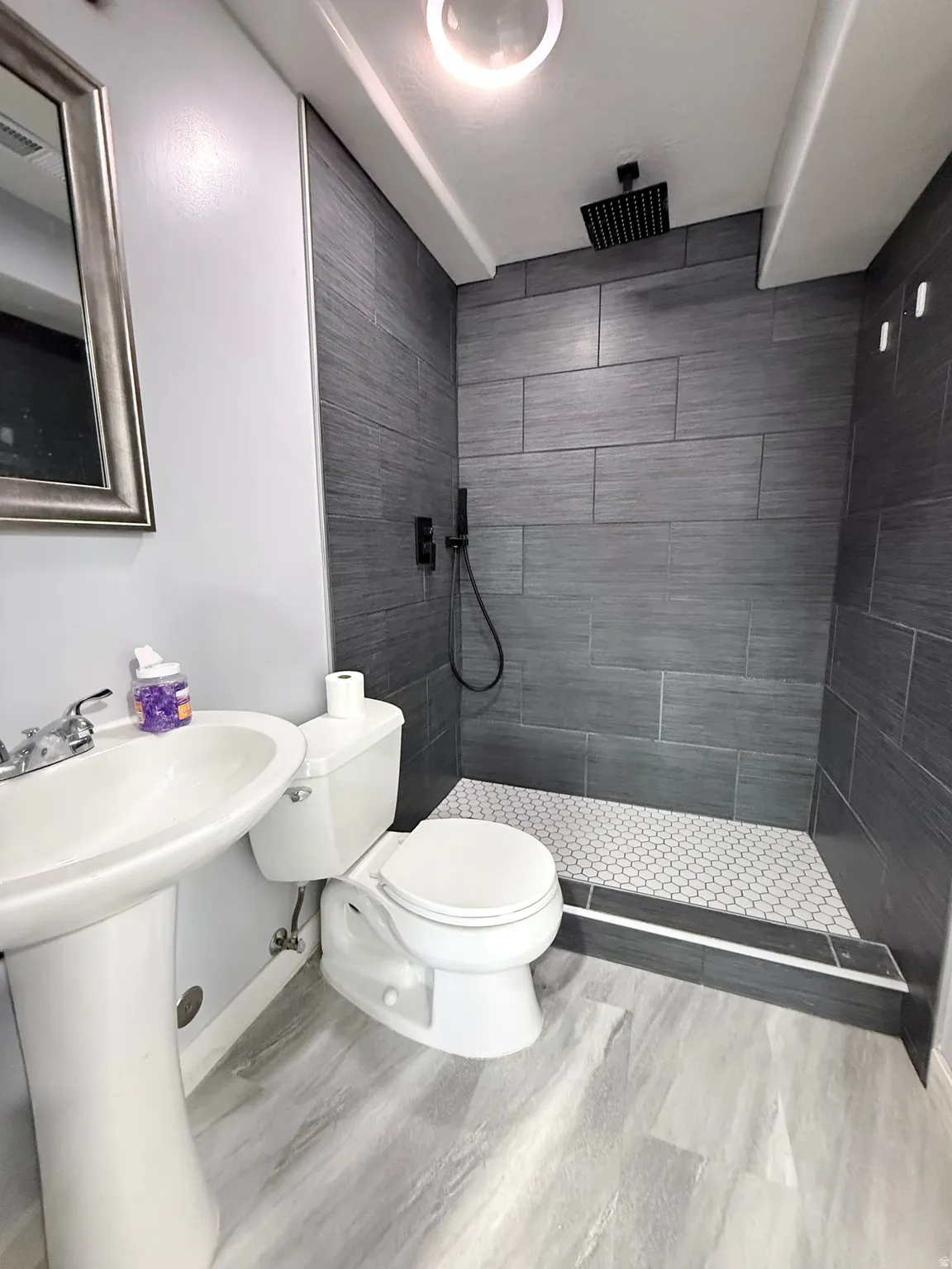 Full bath featuring tiled shower and wood finished floors