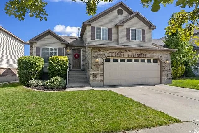 Traditional-style house featuring brick siding, a front yard, driveway, and an attached garage