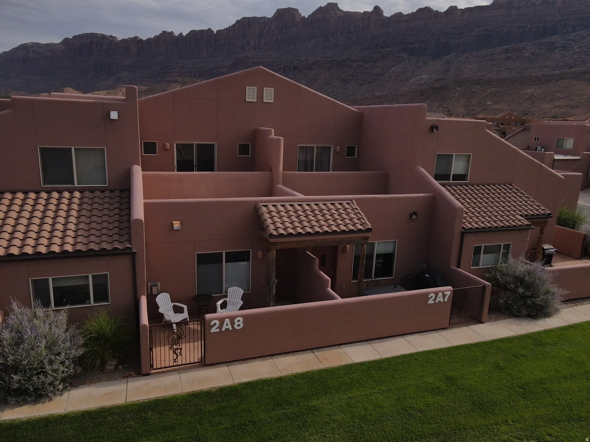 Rear view of house featuring a gate, a mountain view, stucco siding, a tiled roof, and a fenced front yard