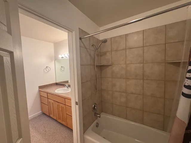 Bathroom with shower / bathtub combination with curtain, vanity, and light carpet