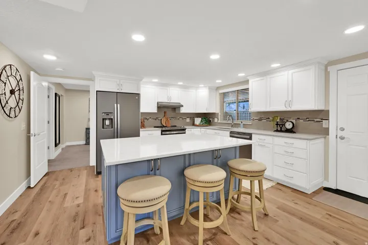Kitchen with white cabinets, a breakfast bar area, recessed lighting, a kitchen island, and light wood-style flooring
