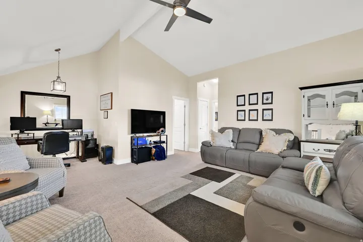 Carpeted living room featuring high vaulted ceiling, a desk, beamed ceiling, and ceiling fan
