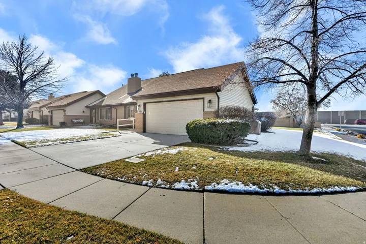 View of front of home featuring brick siding, driveway, a chimney, an attached garage, and a front yard