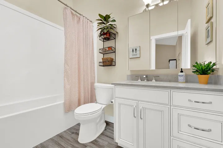 Full bath with shower / tub combo with curtain, vanity, and light wood-style flooring