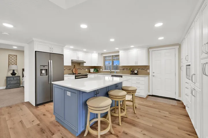 Kitchen featuring blue cabinetry, stainless steel fridge, a kitchen bar, white cabinets, and a kitchen island